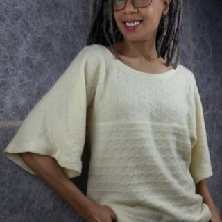 Black woman with glasses and dreadlocks wearing ivory sweater